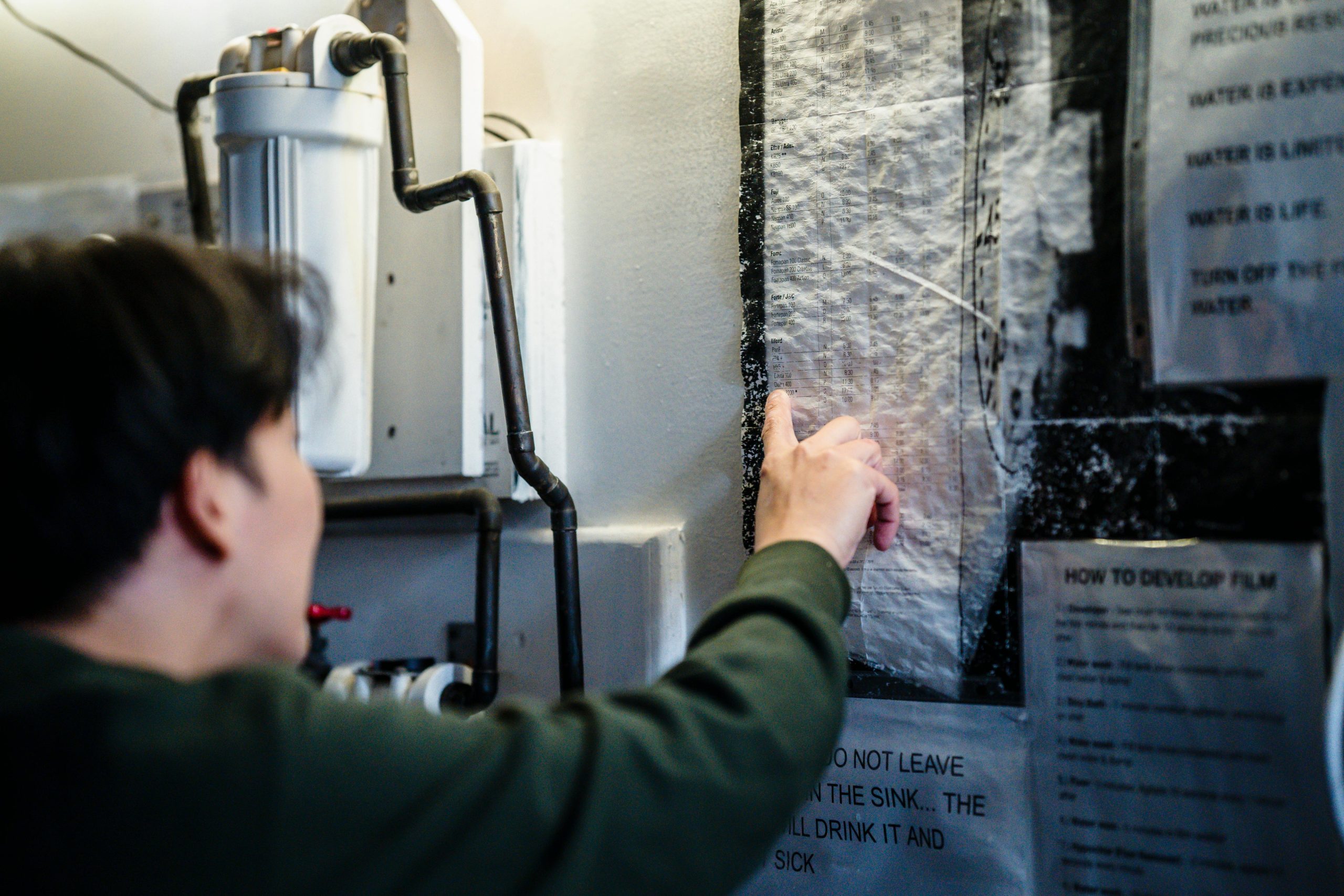Person checking indoor pipes and walls for leaks during a winter plumbing inspection.